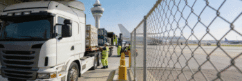 A heavy transport truck being loaded with commercial cargo outside Dubai Airport to ensure continuous supply chain operations.